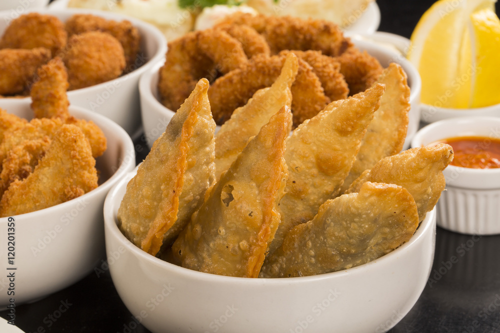 Mixed brazilian snacks, including pastries, fried chicken, salad Mixed brazilian snacks, including pastries, fried chicken, salad