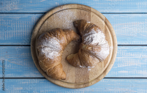 Fresh golden croissants on blue wooden table. Country style.