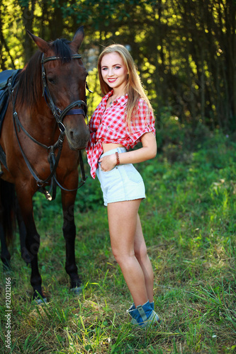 девушка блондинка, гуляет в поле с лошадью 