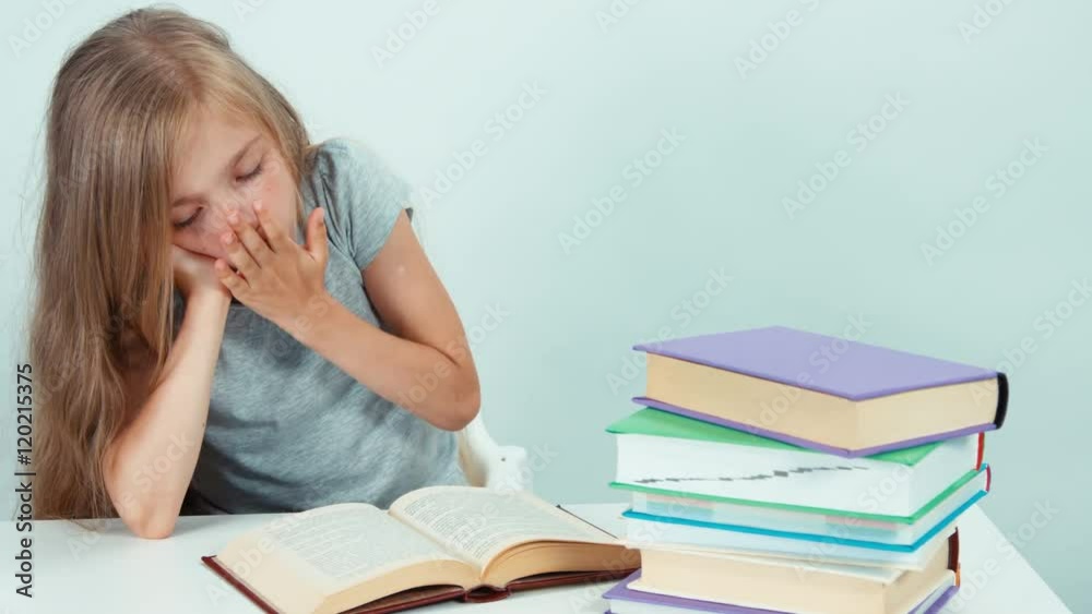 Portrait tired girl yawning and reading a book and looking at the camera Portrait tired girl yawning and reading a book and looking at the camera