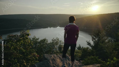 Woman stands on the mountain rocks and admiring a buatiful view photo