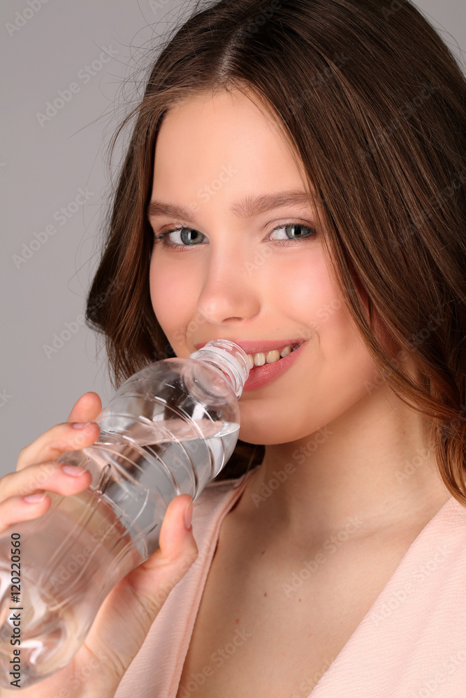 Girl in pink top drinking water. Close up. Gray background Girl in pink top drinking water. Close up. Gray background