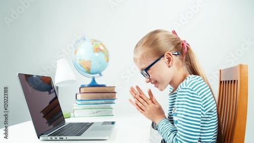 Schoolgirl child 7-8 years using credit card and her laptop and smiling with smile at camera photo