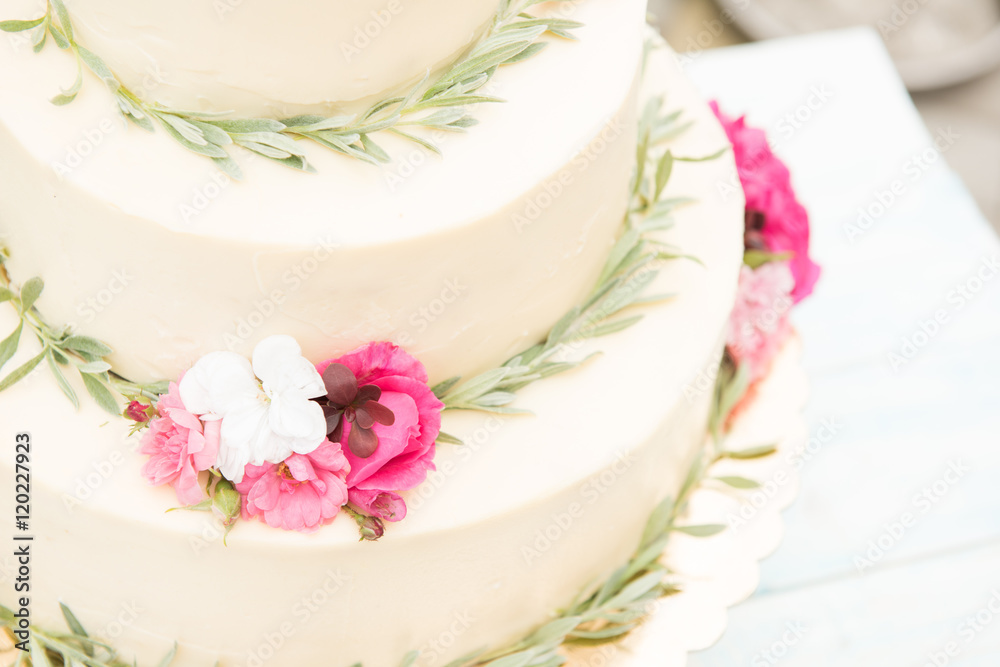 Beautiful wedding cake with flowers on table, outdoors. Three levels