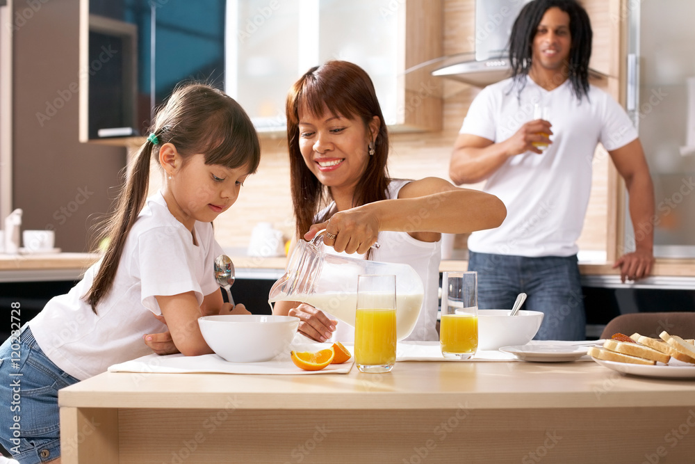 Mother cooking cereal with her daughter nearby in the kitchen