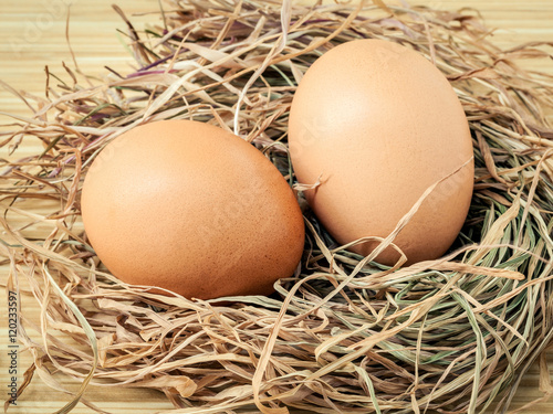 Closeup brown chicken eggs in a straw nest . Fresh organic eggs