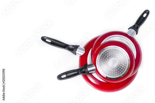 Induction frying pans of different sizes, red colored. Isolated on white with blank space at left