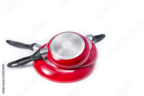 Induction frying pans of different sizes, red colored. Isolated on white with blank space at top and right