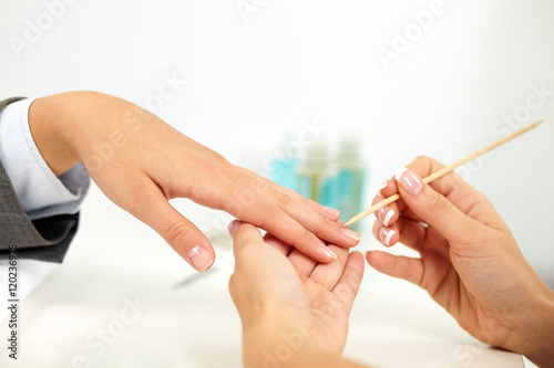 Beautician adjusting cuticle on female hand