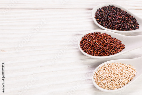 Red, black and white quinoa seeds on a wooden background