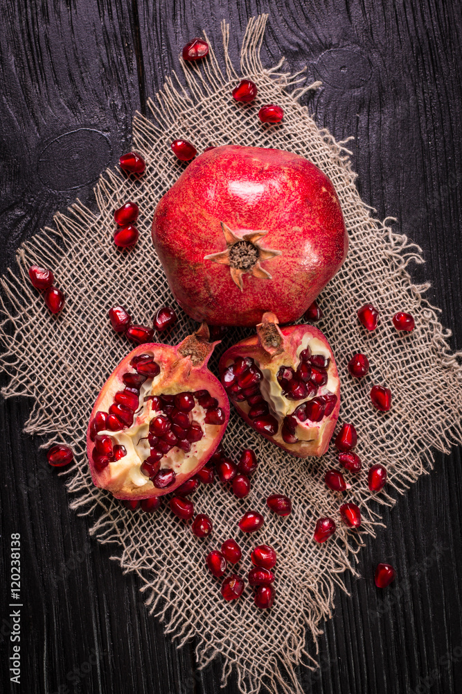 Some red juicy pomegranate, whole and broken, on rustic wooden table Some red juicy pomegranate, whole and broken, on rustic wooden table