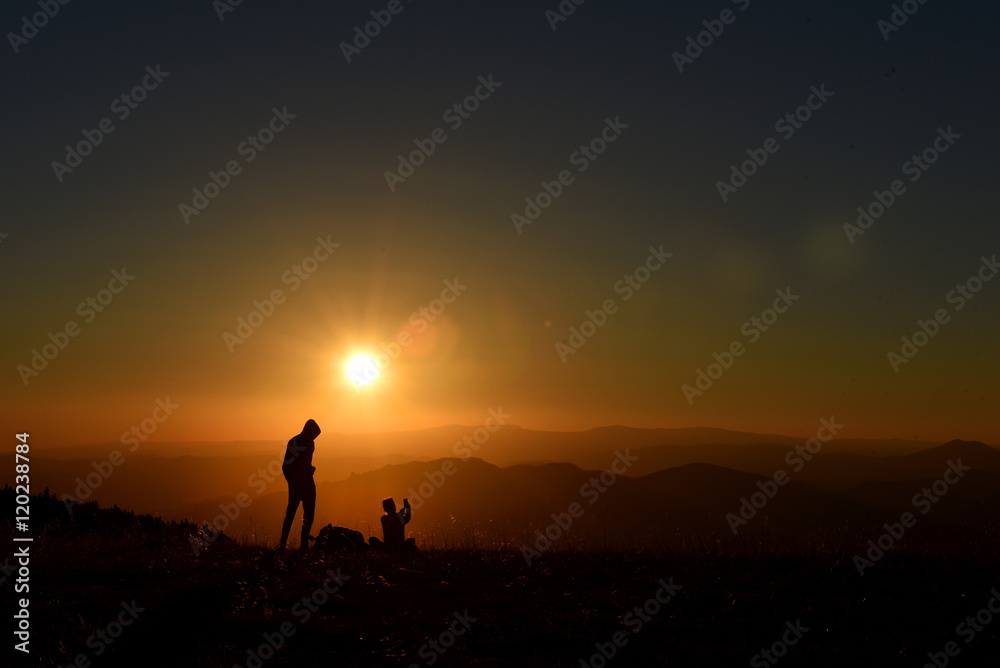 People relaxing and enjoying sunset in the mountains