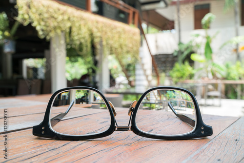 Clear Eyeglasses Glasses with Black Frame Fashion Vintage Style on Wood Desk Background 