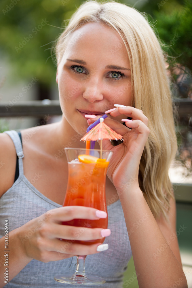 young woman drinks cocktail outdoor on a hot summer afternoon in young woman drinks cocktail outdoor on a hot summer afternoon in