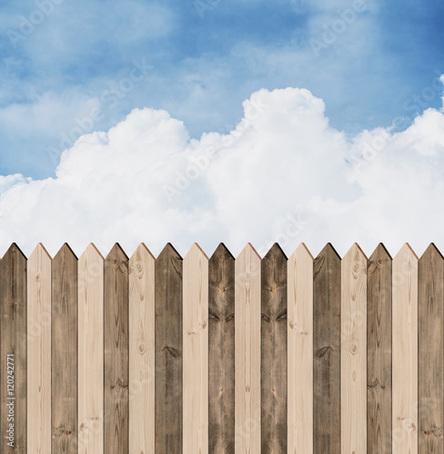 Wooden picket fence with blue sky and clouds