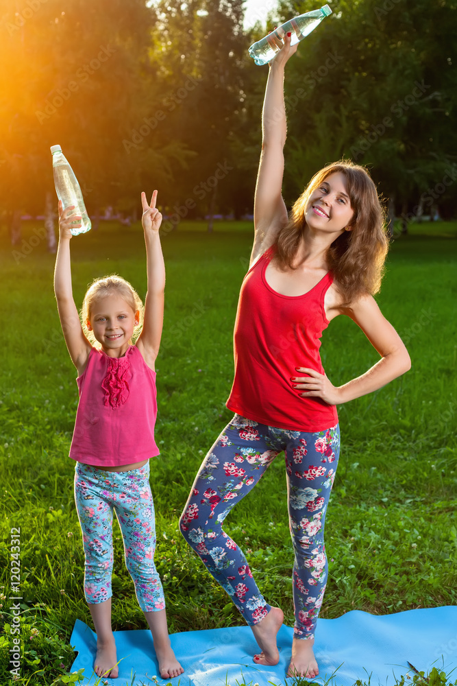 Obraz premium Mother and her daughter outdoors doing yoga