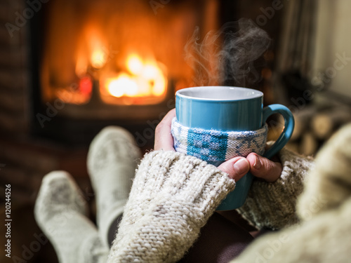 Warming and relaxing near fireplace with a cup of hot drink.