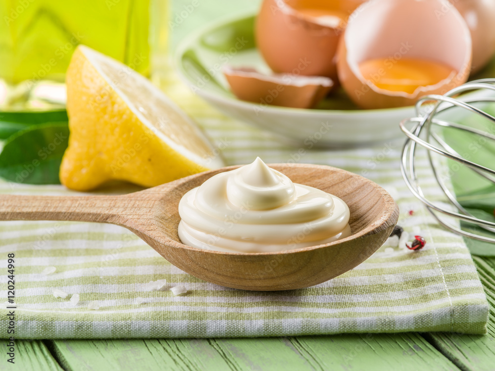 Natural mayonnaise sauce in the wooden spoon and its ingredient Natural mayonnaise sauce in the wooden spoon and its ingredient