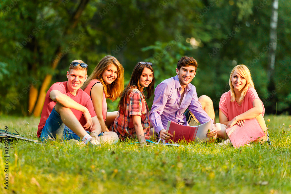 group of happy students with books in the Park on a Sunny day