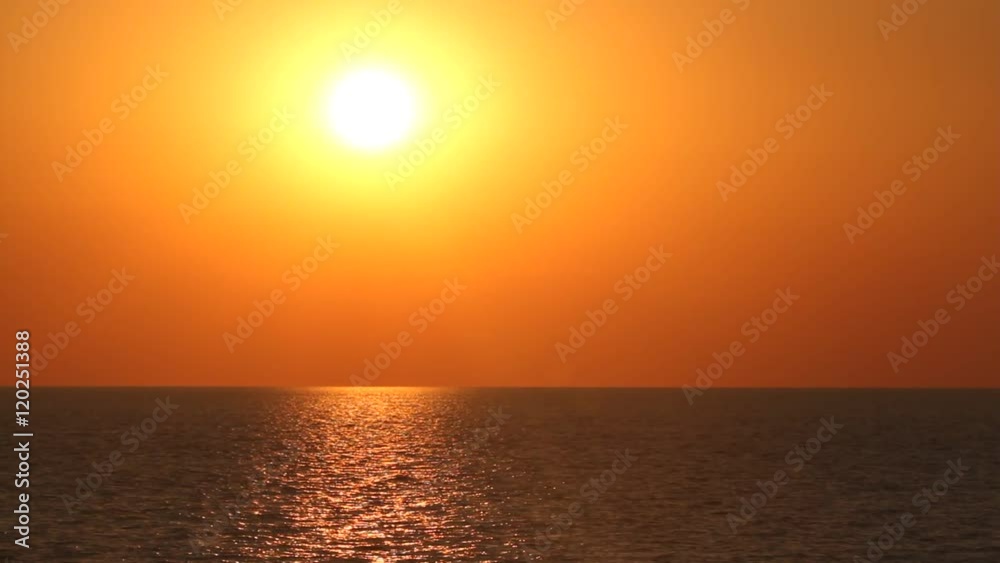 Sunset on a sea with white sun disc, red sky and dark blue or grey wavy water surface with the sun reflections. Also birds which cross the sky are visible. Sunset on a sea with white sun disc, red sky and dark blue or grey wavy water surface with the sun reflections. Also birds which cross the sky are visible.