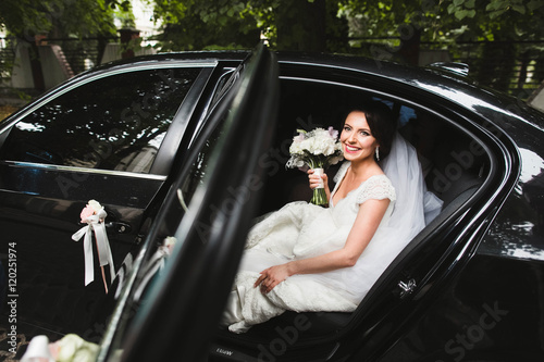 bride sitting in a stylish black foreign car