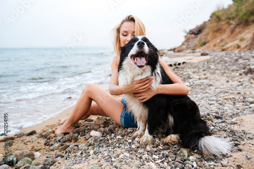 Happy woman hugging her dog on the beach