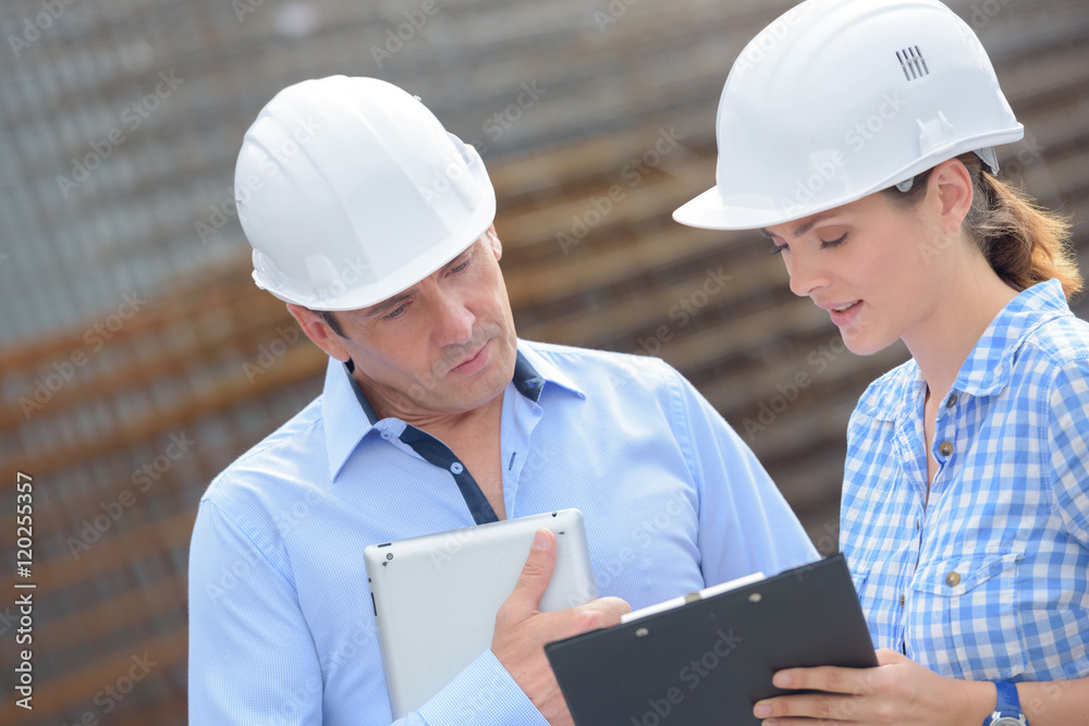 Man and woman in hardhats looking at clipboard Man and woman in hardhats looking at clipboard