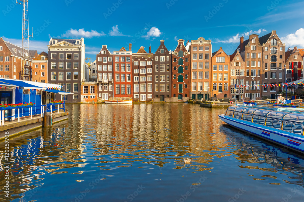 Beautiful typical Dutch dancing houses at the Amsterdam canal Damrak in the sunny evening, Holland, Netherlands.