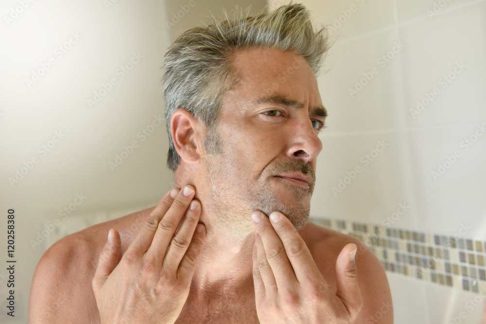 Obraz premium Mature man in bathroom checking beard