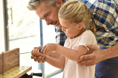 Daddy teaching daughter how to use screwdriver photo