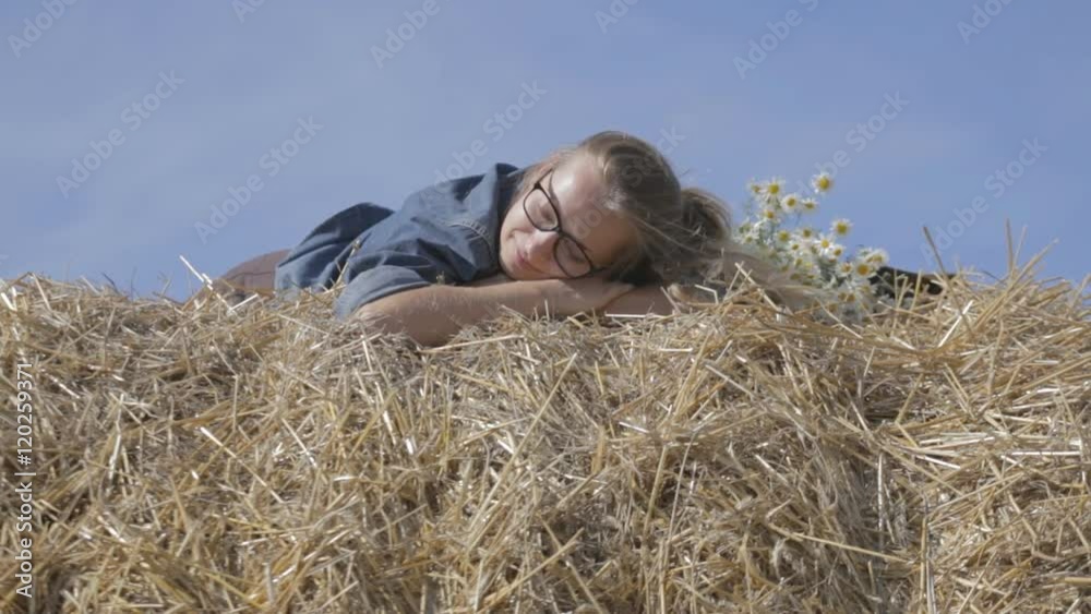 girl lying on a stack of straw with a bouquet of white daisies. girl lying on a stack of straw with a bouquet of white daisies.