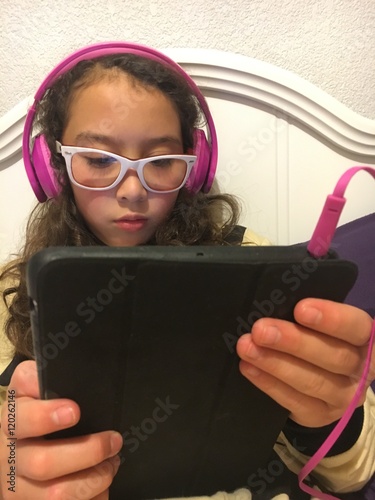 Niña con audifonos viendo una tablet photo