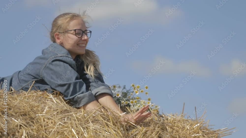 girl lying on a stack of straw with a bouquet of white daisies. girl lying on a stack of straw with a bouquet of white daisies.