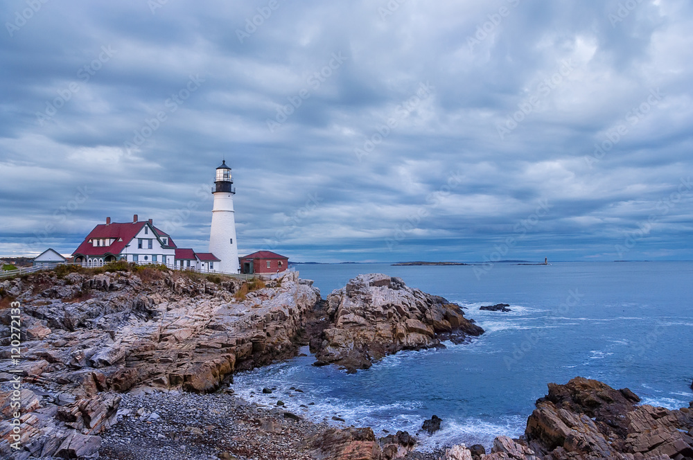 Lighthouse on the ocean, Portland. Maine United States. dusk, dark time, heavy low clouds, stormy sky.  Night. clouds running at slow shutter speeds
