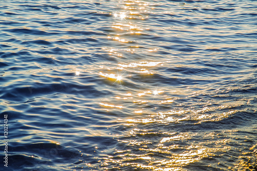 Blue sea water surface at sunset with sparks
