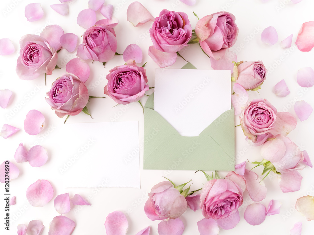 Paper envelop with white card and pink roses. Flat lay, top view