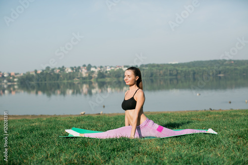 Young woman doing yoga in morning park near lake  © anatoliycherkas