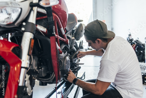 man repairing his motorcycle photo