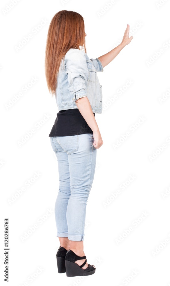back view of woman. Young woman in jeans presses down on something. Isolated over white background. Rear view people collection. backside view of person. she holds his hand open, palm forward back view of woman. Young woman in jeans presses down on something. Isolated over white background. Rear view people collection. backside view of person. she holds his hand open, palm forward