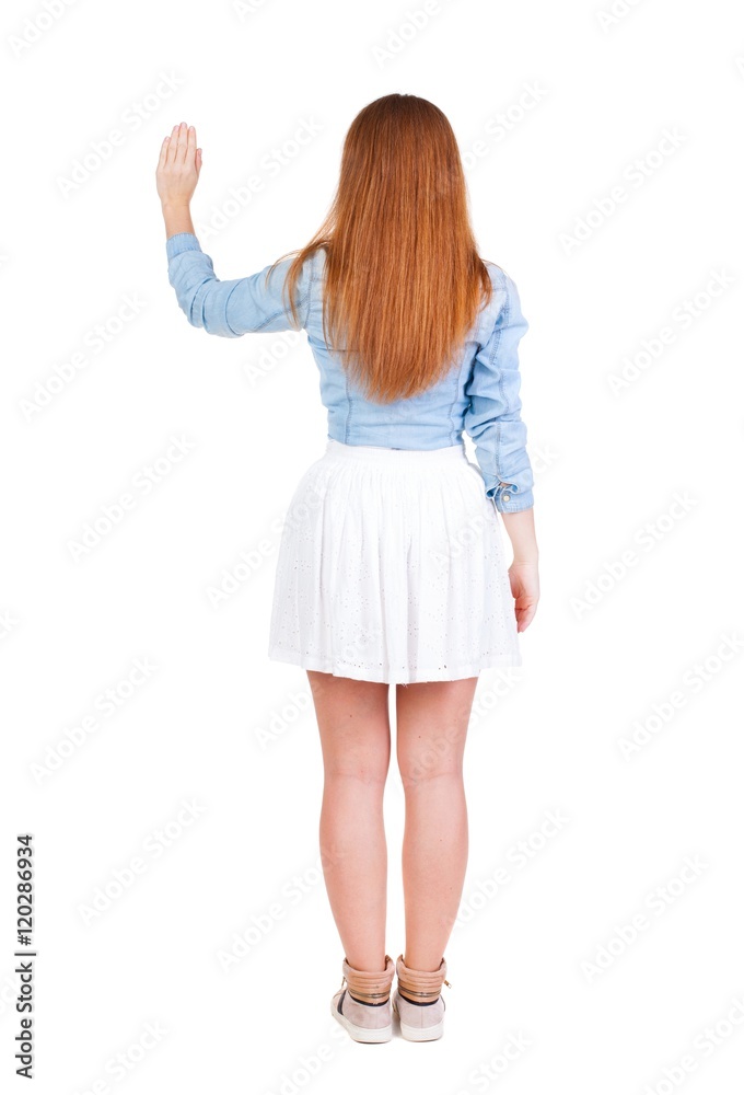 Naklejka premium back view of woman. Young woman in dress presses down on something. Isolated over white background. Rear view people collection. backside view of person. she holds his hand open, palm forward