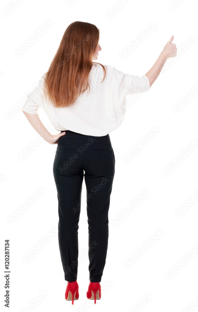 back view of standing young redhead business woman showing thumb up. beautiful businesswoman in black suit gesturing ok sign. Rear view people collection. backside view of person. Isolated over back view of standing young redhead business woman showing thumb up. beautiful businesswoman in black suit gesturing ok sign. Rear view people collection. backside view of person. Isolated over