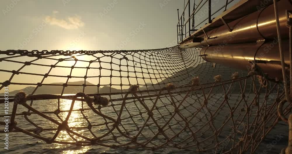 Yacht bow with netting on a calm summer day on the sea at sunset