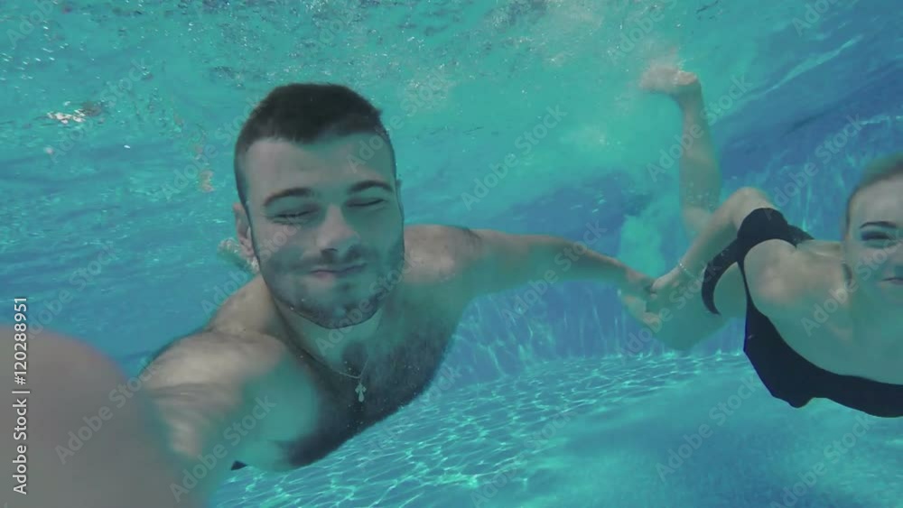 The man with girl swimming under water with camera
