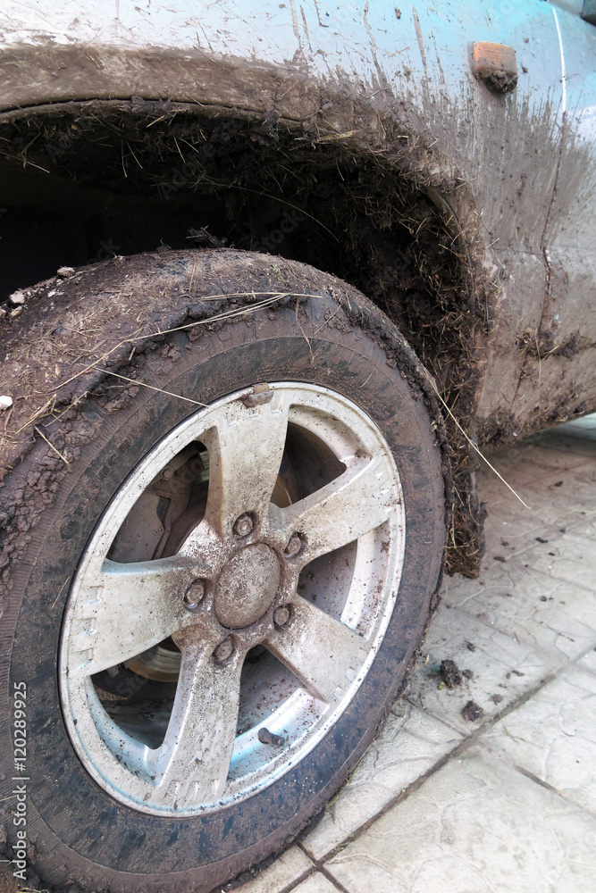 Extremely dirty SUV wheel after driving heavy off-road in the ra