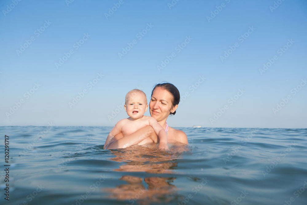 Happy family at sea. Mom keeps daughter in her arms Happy family at sea. Mom keeps daughter in her arms