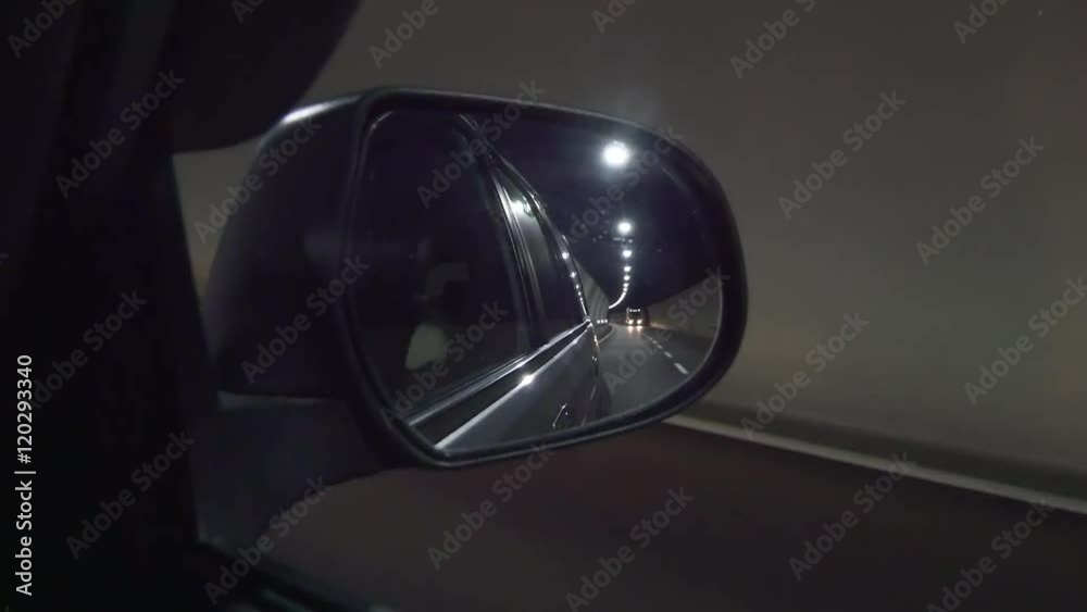 Car driving inside the tunnel with lights. View through the wing mirror