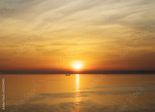 Bright sunset. Tranquil Sea. Fishing boat in the rays of the setting sun