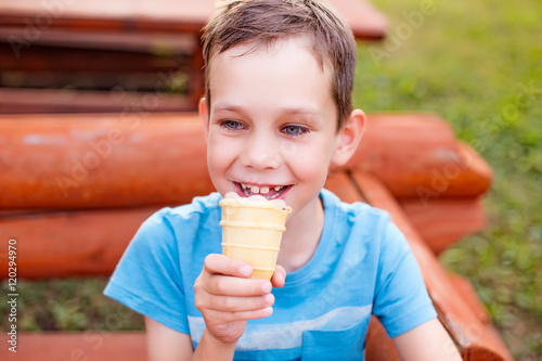 boy enjoying ice cream in a waffle cup. smiling child eating ice cream outdoors. Closeup