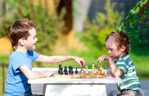 children started the classic a chess match outdoors. two young chess players outdoors. the concept of education