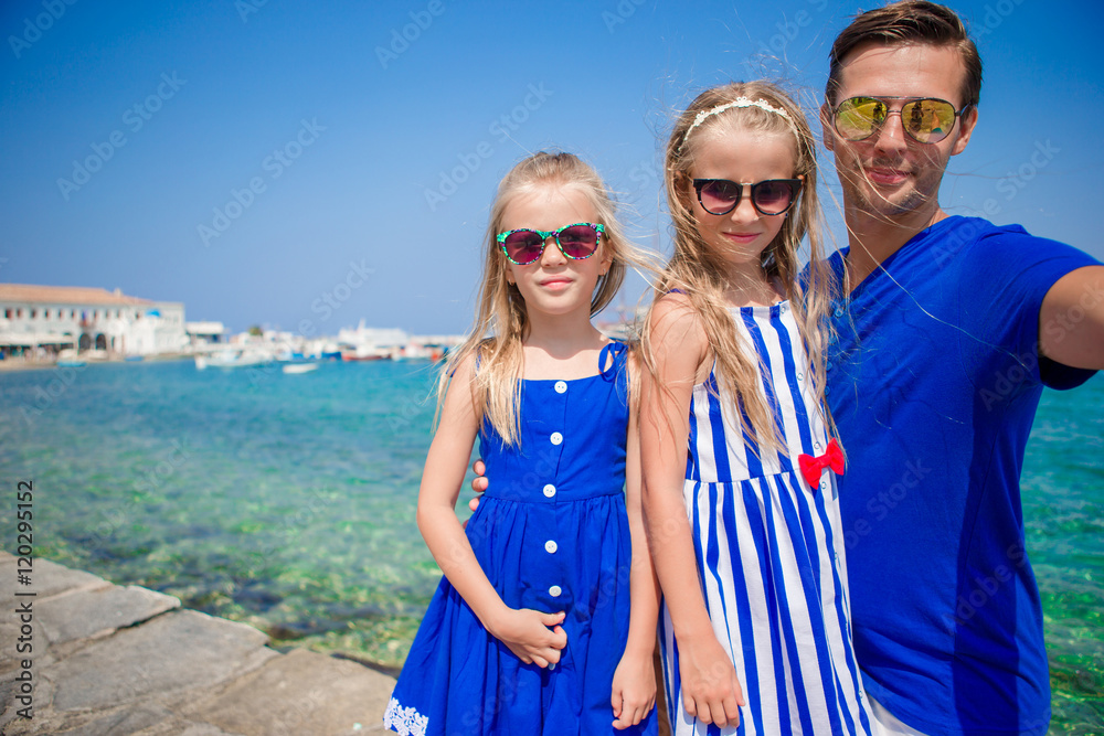 Family vacation in Europe. Father and kids taking selfie background Mykonos town in Greece